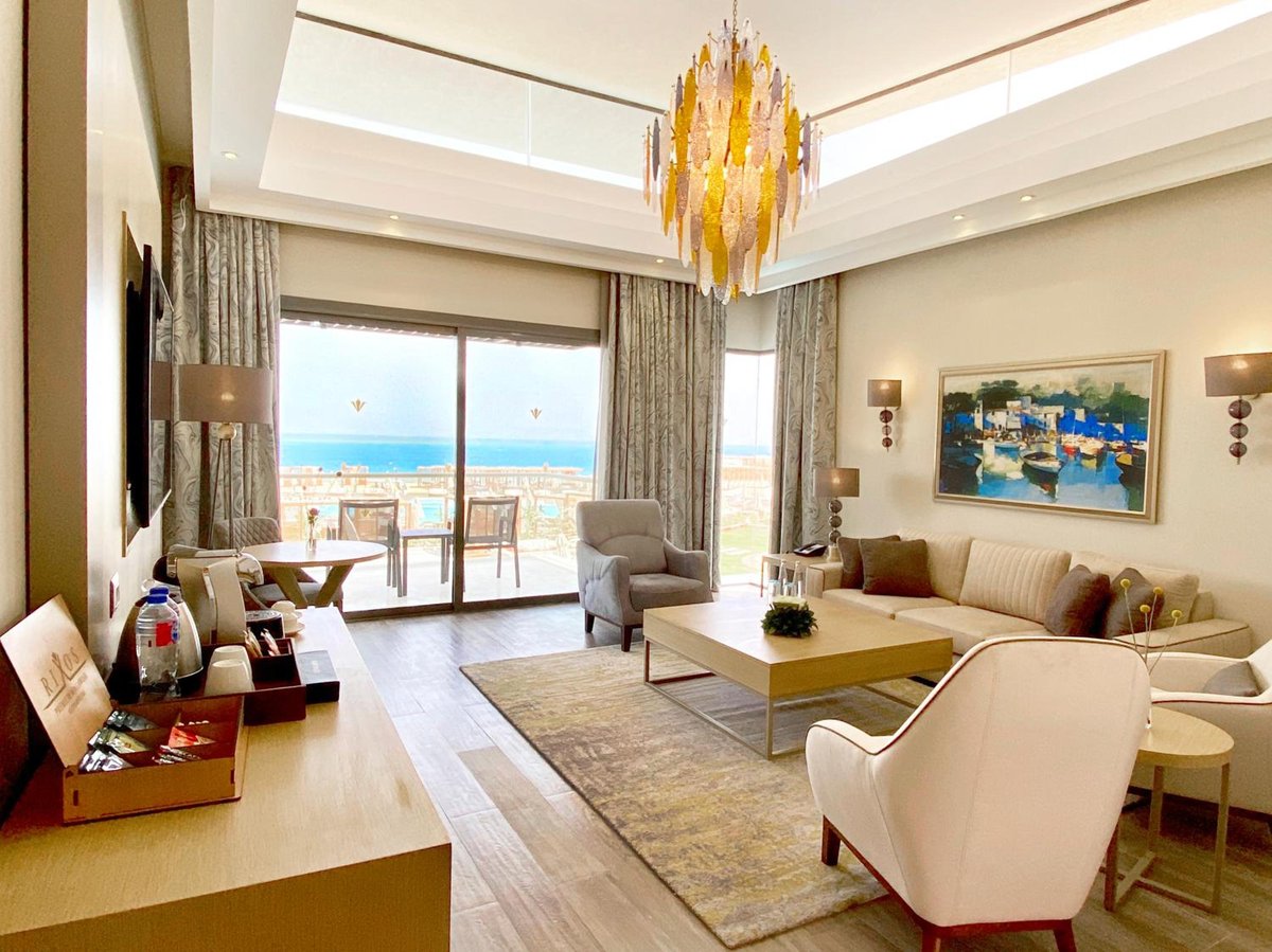 Rixos Premium Magawish Suites & Villas living room with floor-to-ceiling windows and sofa seating.