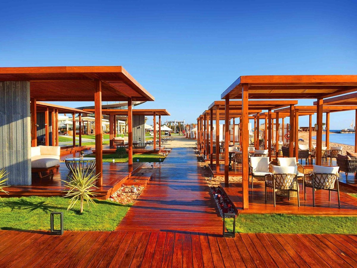 Rixos Premium Magawish Suites & Villas cabana walkway with wooden pergolas and a red deck.