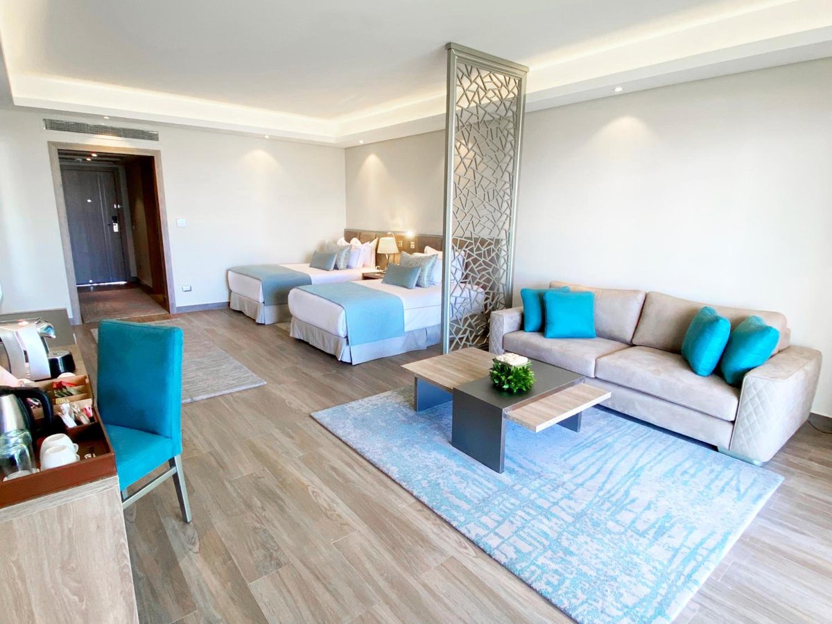 Rixos Premium Magawish Suites & Villas guest suite with two beds and a sofa.