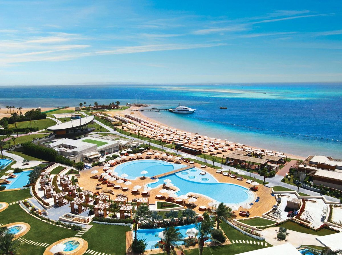 Rixos Premium Magawish Suites & Villas pool area with curved pools and a sandy beach.