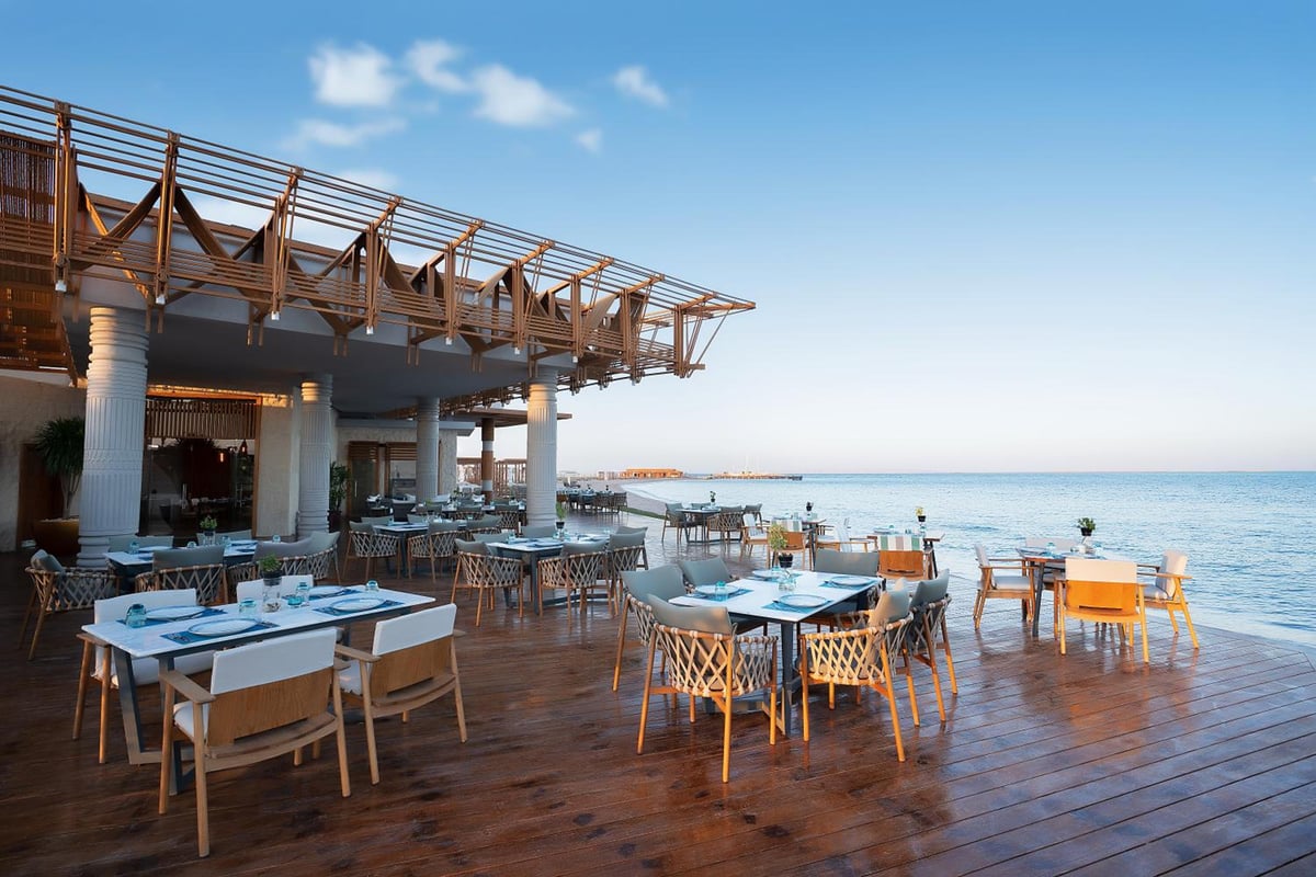 Rixos Premium Magawish Suites & Villas outdoor dining terrace with sea views and a timber pergola.
