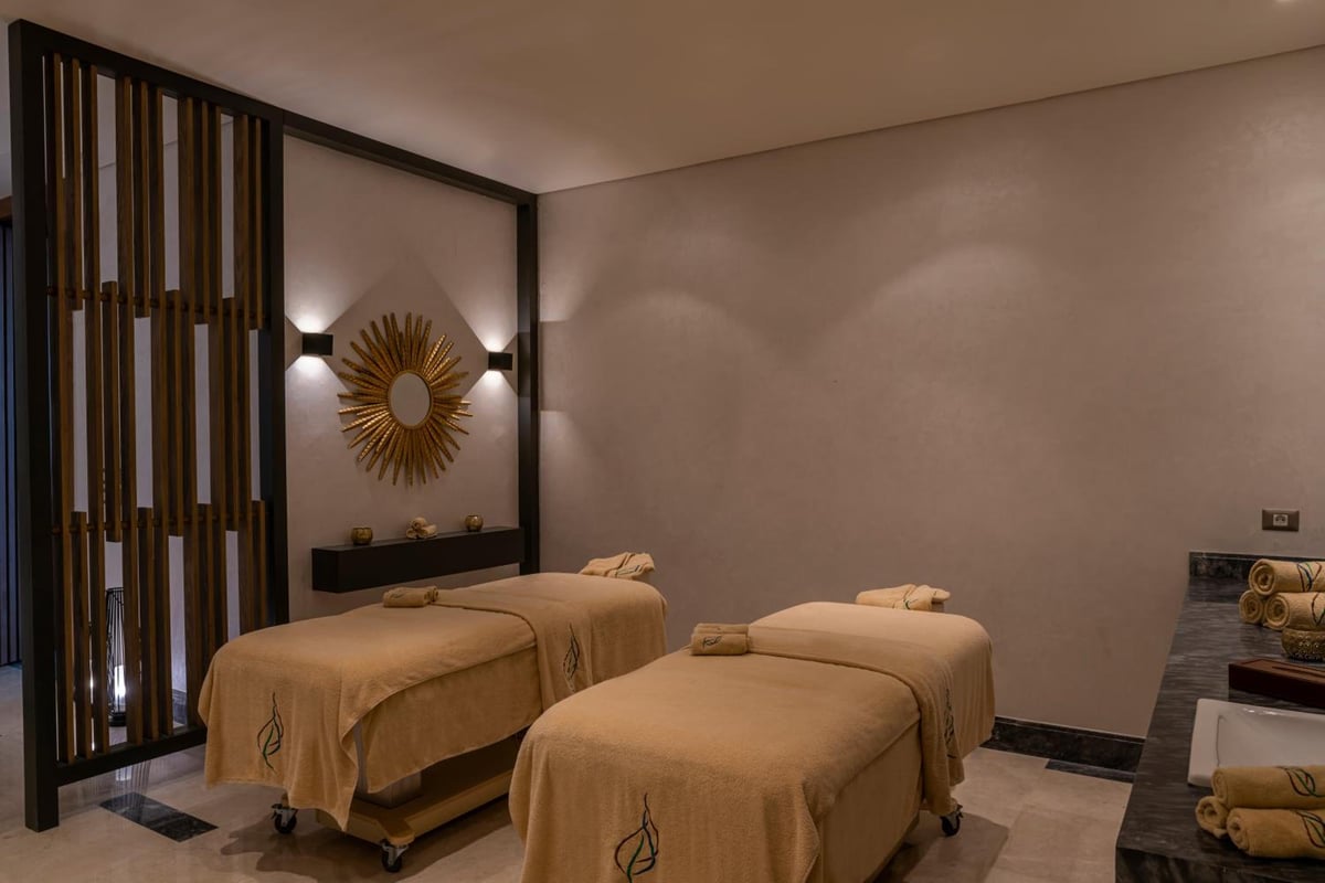 Rixos Premium Magawish Suites & Villas massage room with two treatment beds and a wooden slat partition.