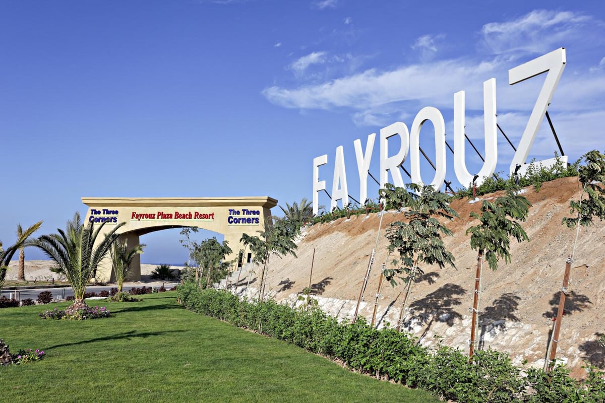 Three Corners Fayrouz Plaza Beach Resort entrance with a stone wall and large white lettering.