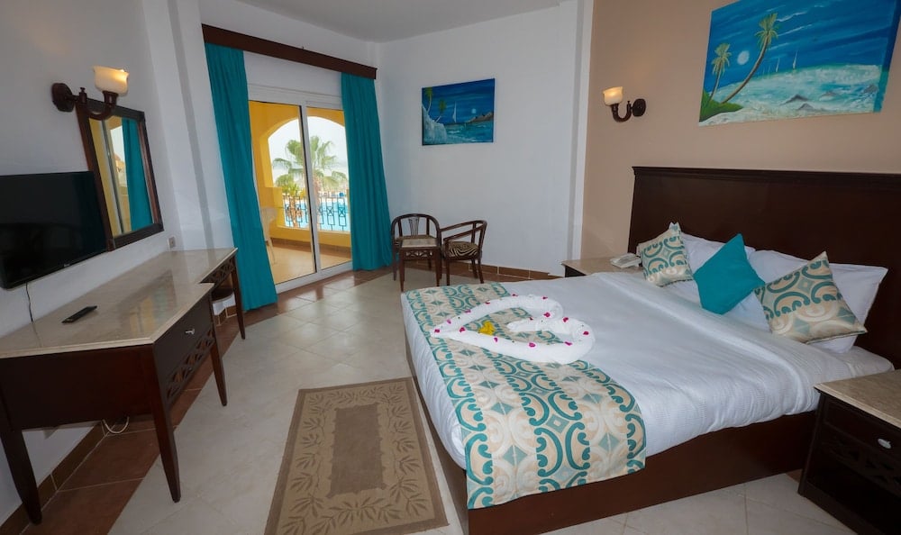 Blue Reef Marsa Alam guest room with a double bed and teal curtains.