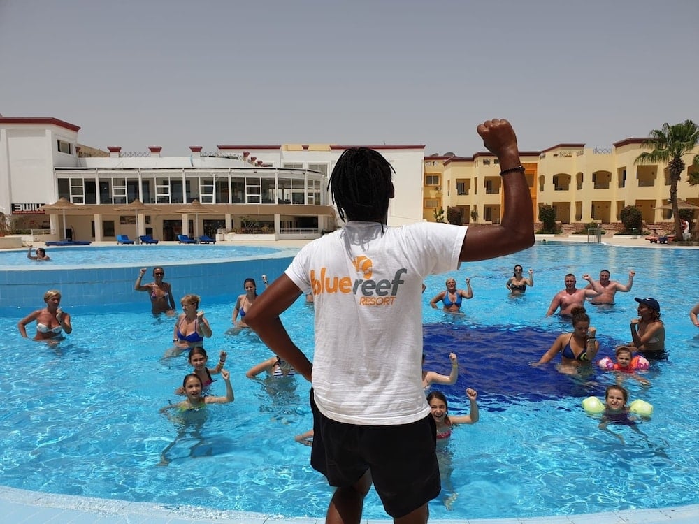 Blue Reef Marsa Alam pool with swimmers and a person raising an arm.