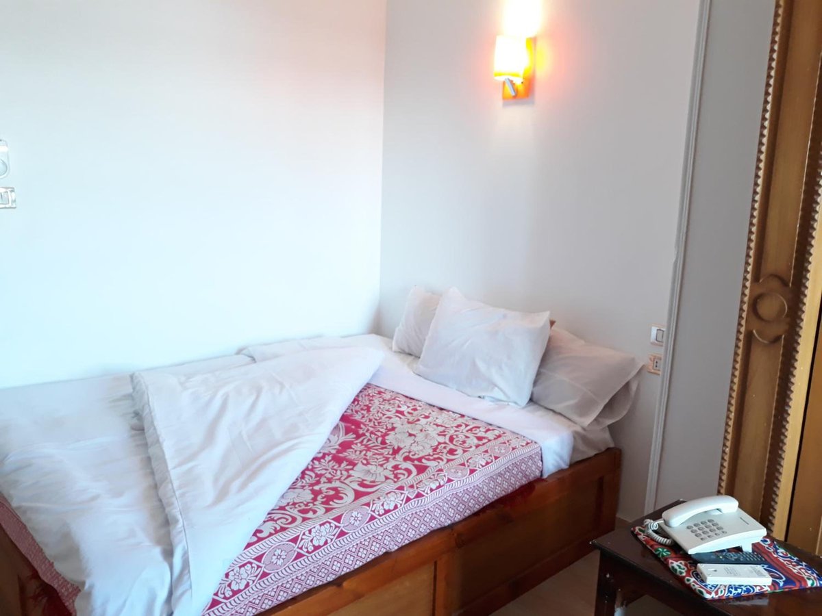 El Mesala Hotel Luxor bedroom with white bedding and a red patterned bedspread.