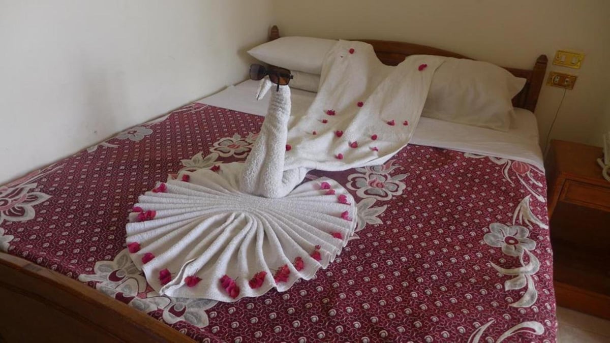El Mesala Hotel Luxor bedroom with a patterned bedspread and towel swans.