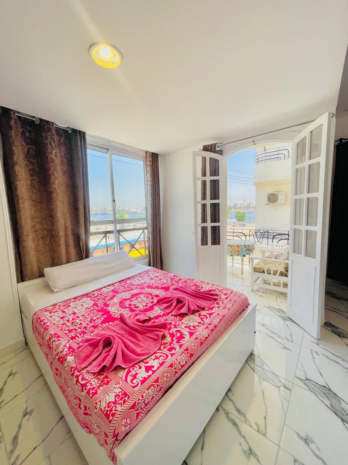 El Mesala Hotel Luxor bedroom with a patterned bedspread and open doors to a balcony.