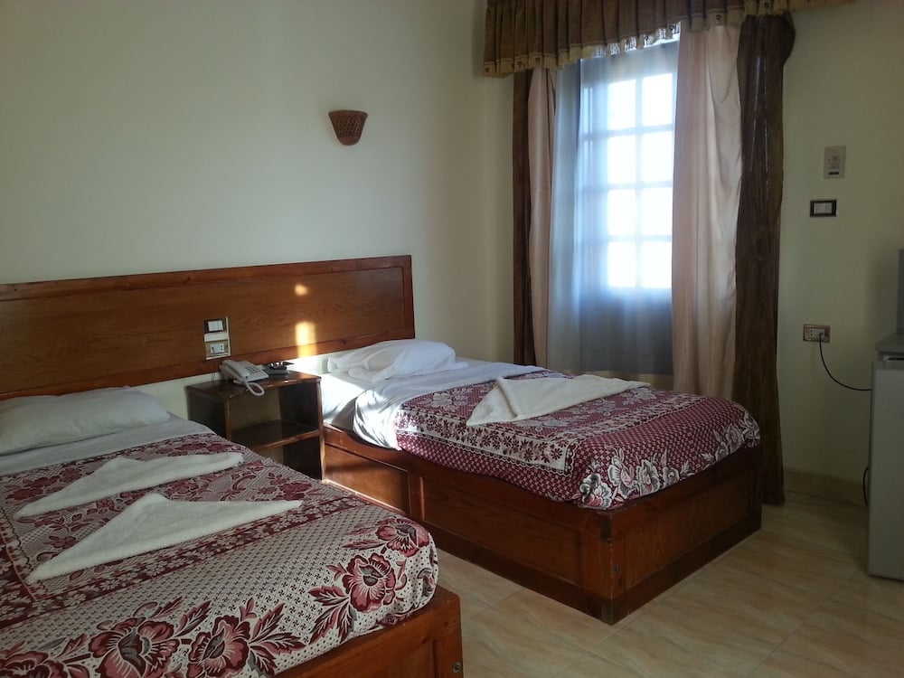 El Mesala Hotel Luxor twin bedroom with patterned bedspreads and a curtained window.