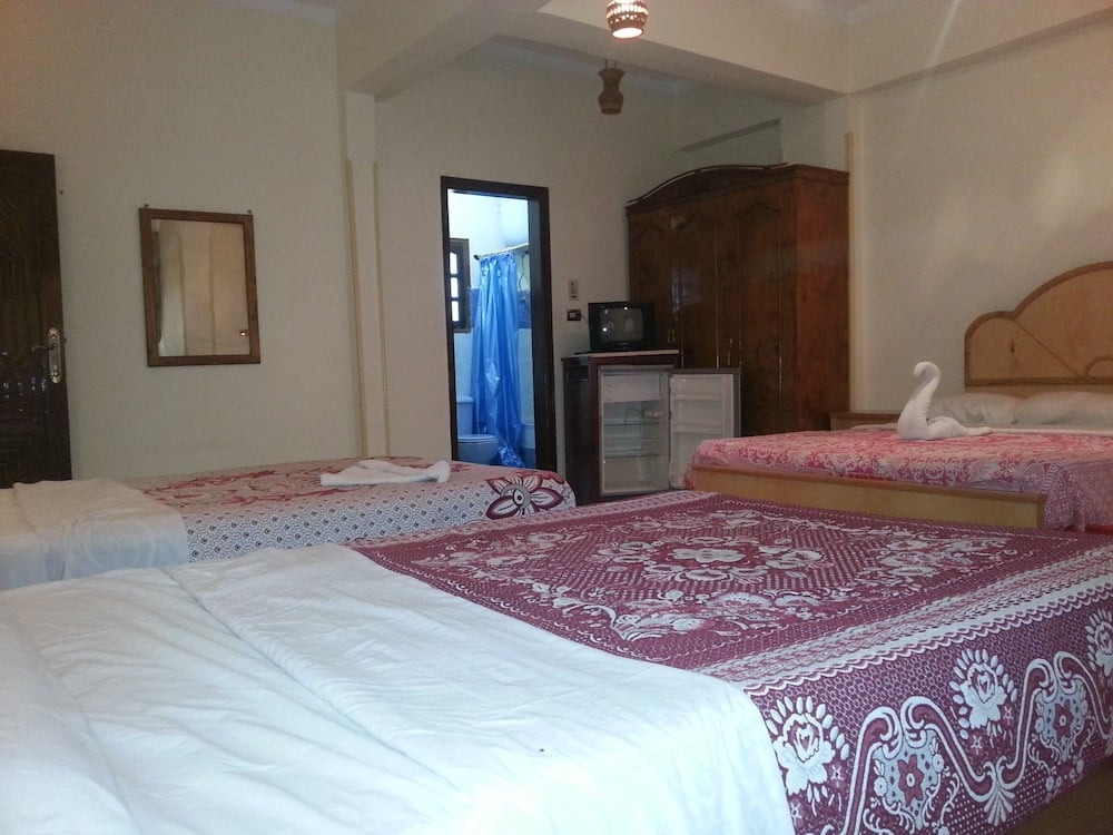 El Mesala Hotel Luxor bedroom with patterned beds and a wooden wardrobe.