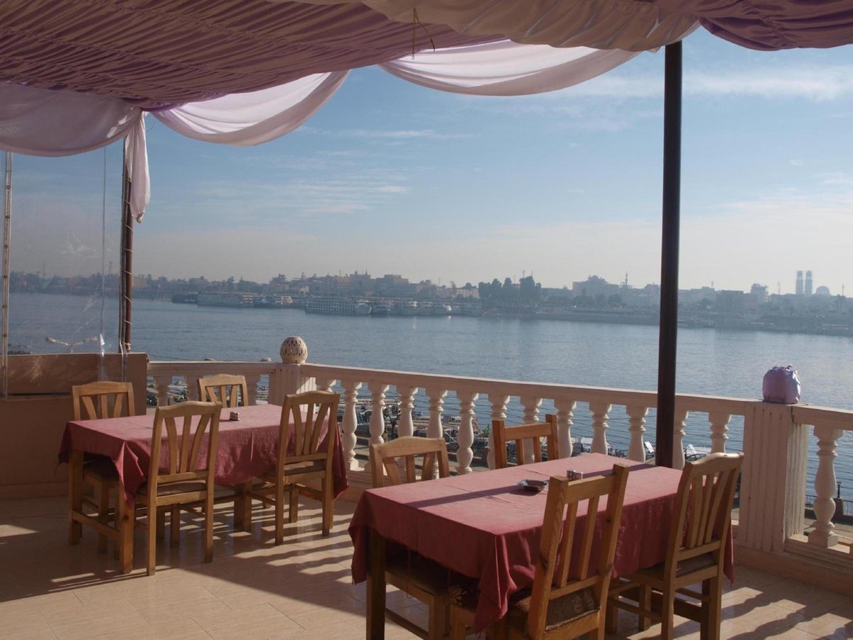 El Mesala Hotel Luxor dining terrace with red tablecloths and a river view.