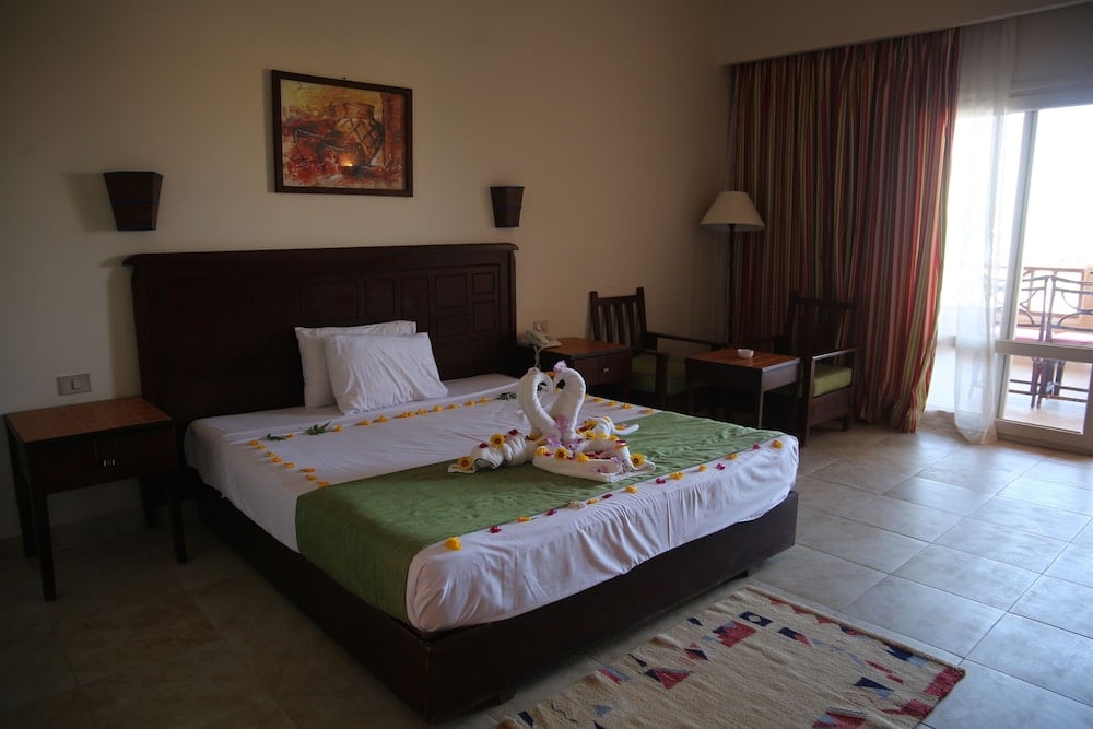 Laguna Beach Marsa Resort bedroom with a large bed and balcony doors.