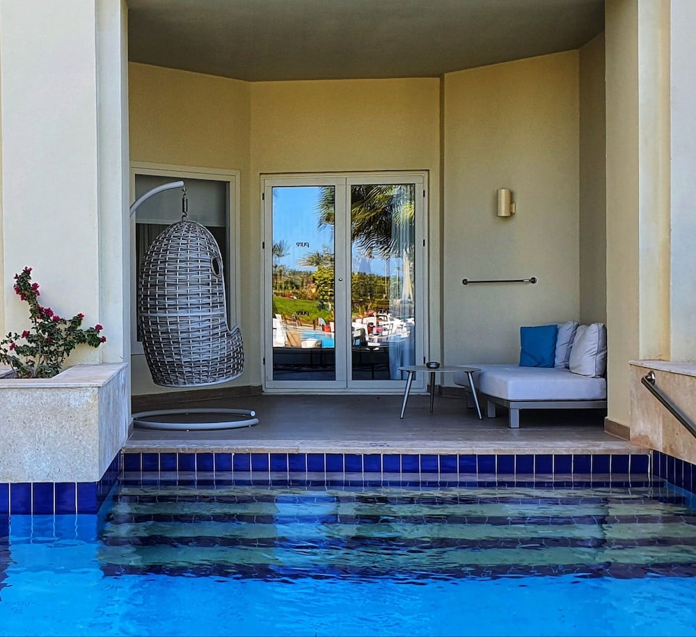 Steigenberger Pure Lifestyle (Adults Only) pool patio with a blue-tiled pool and a hanging chair.