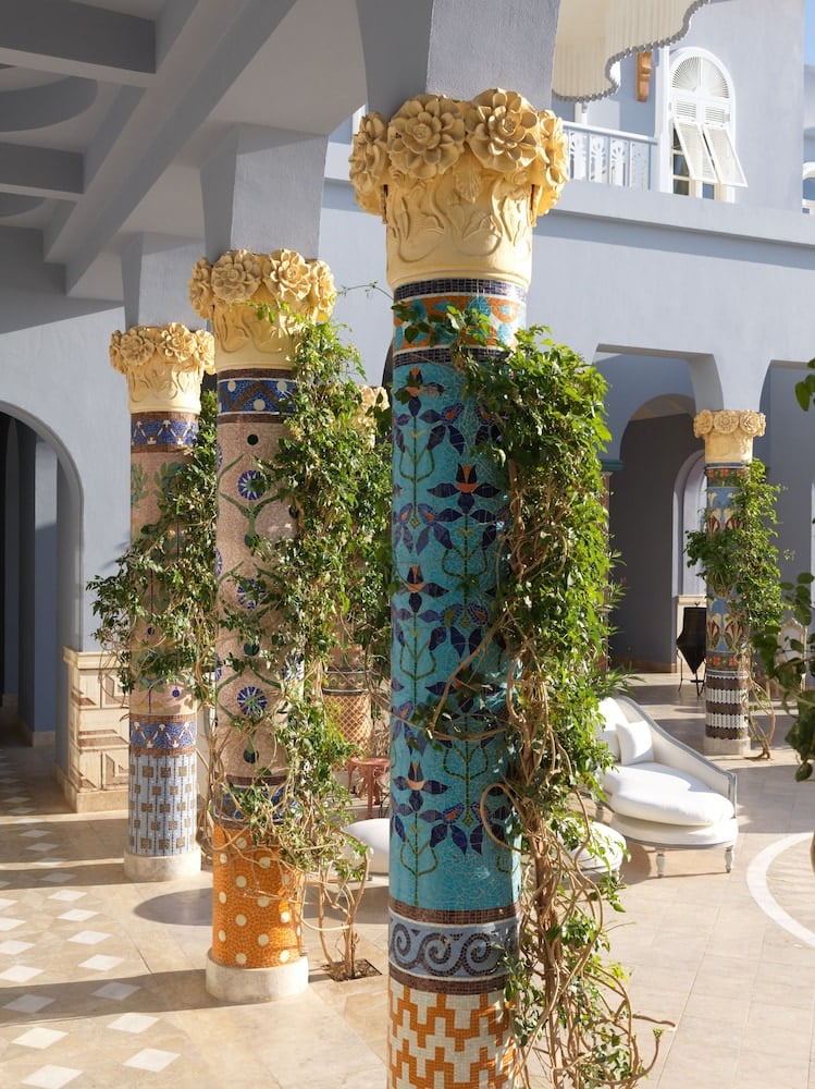 La Maison Bleue El Gouna courtyard with mosaic-tiled columns and climbing plants.
