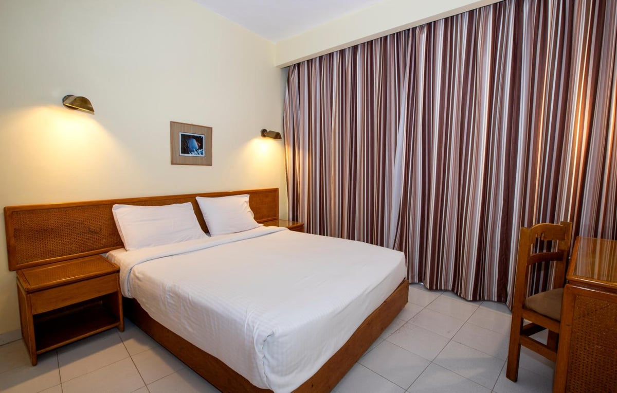 Sunny Days Mirette Family Resort bedroom with white bedding and striped curtains.