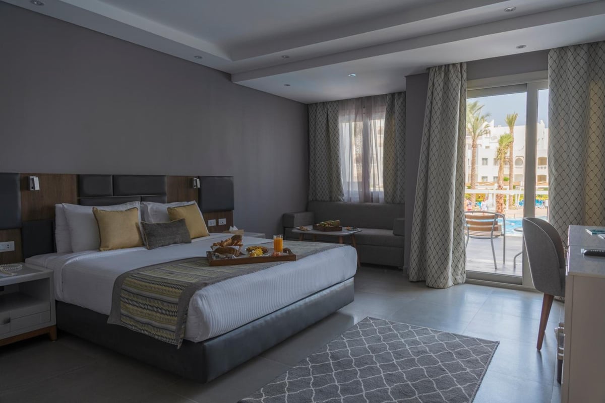Sunrise Diamond Beach Resort Grand Select guest room with a large bed and balcony doors.