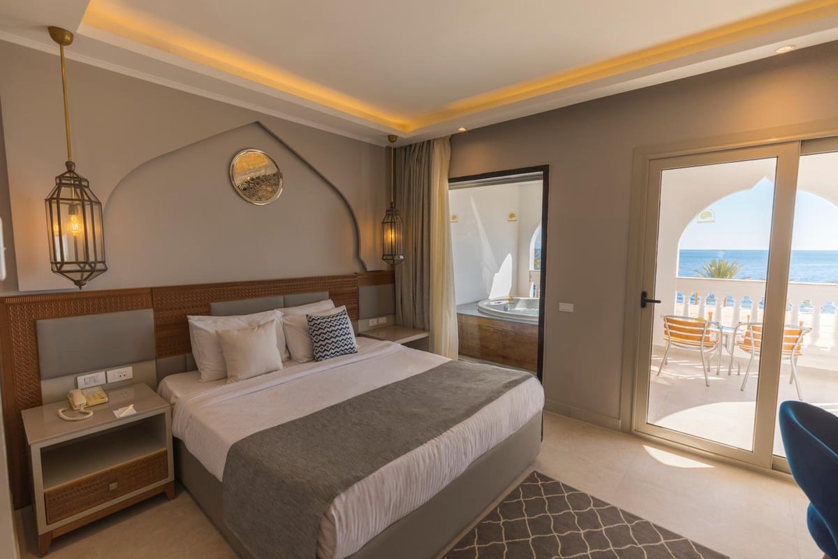 Sunrise Diamond Beach Resort Grand Select bedroom with a large bed and glass balcony doors.