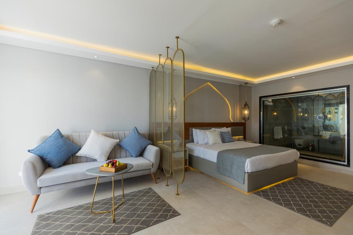 Sunrise Diamond Beach Resort Grand Select bedroom with a sofa and glass bathroom partition.