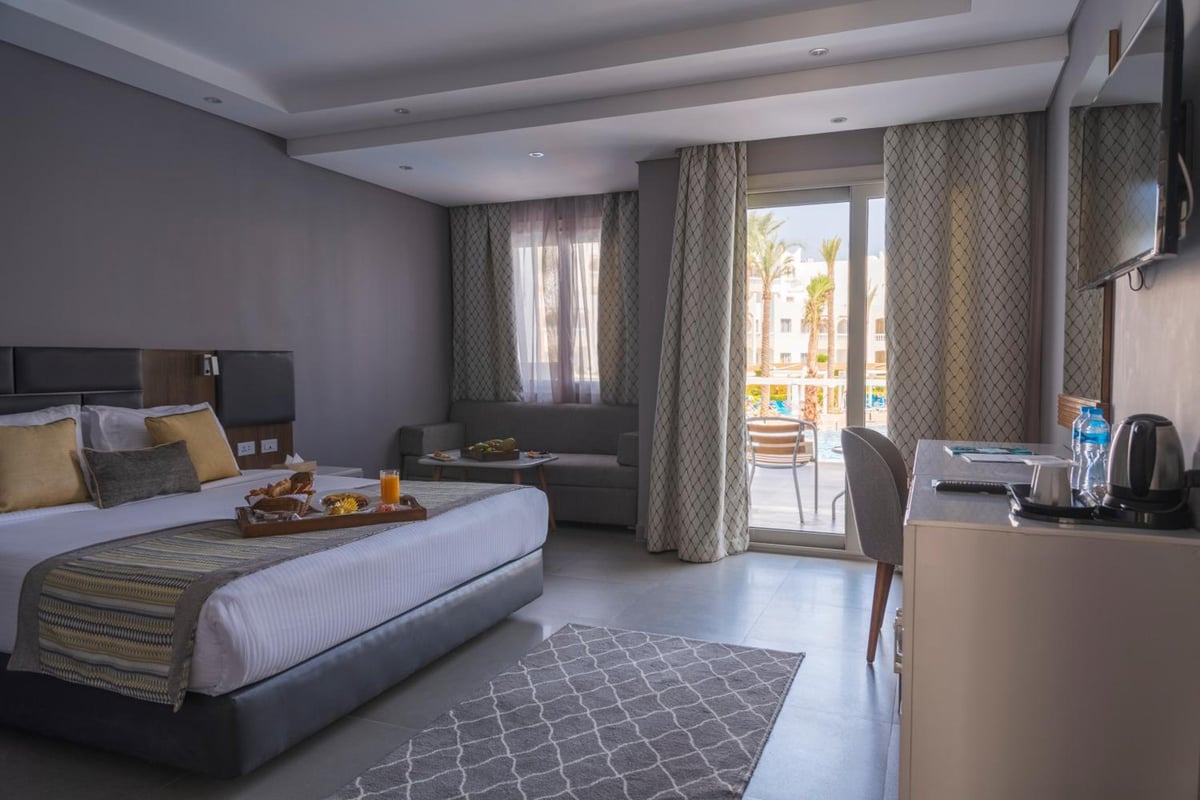 Sunrise Diamond Beach Resort Grand Select bedroom with a bed and sliding glass doors.