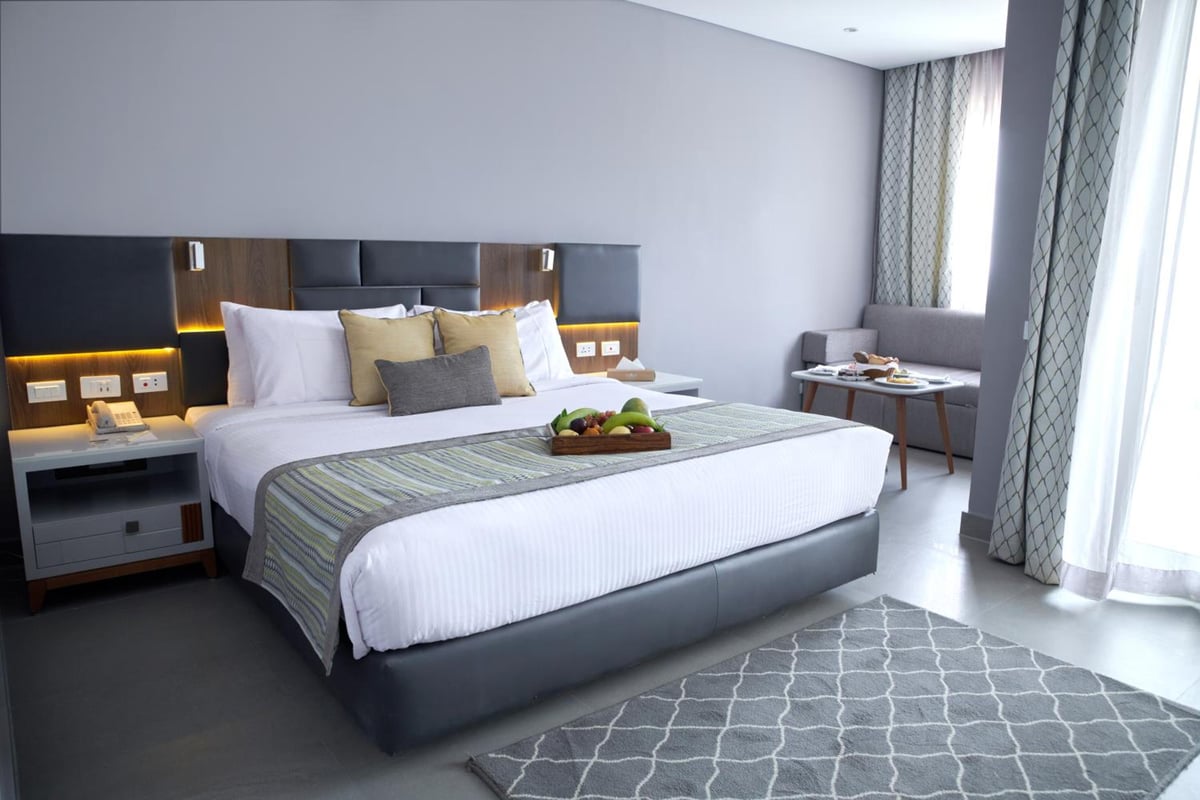 Sunrise Diamond Beach Resort Grand Select guest bedroom with a large bed and floor-to-ceiling curtains.