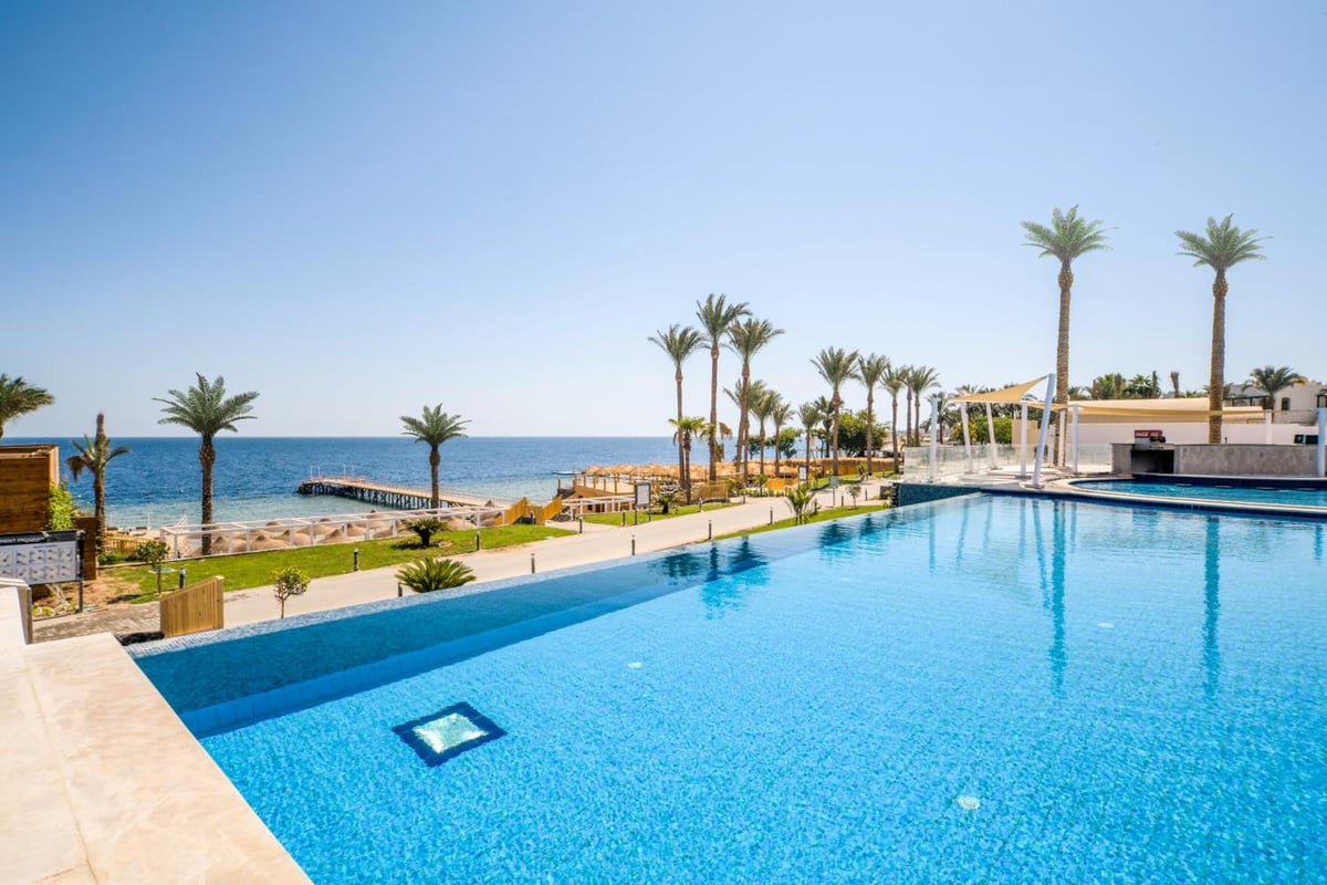 Sunrise Diamond Beach Resort Grand Select outdoor pool with a sea view and palm trees.
