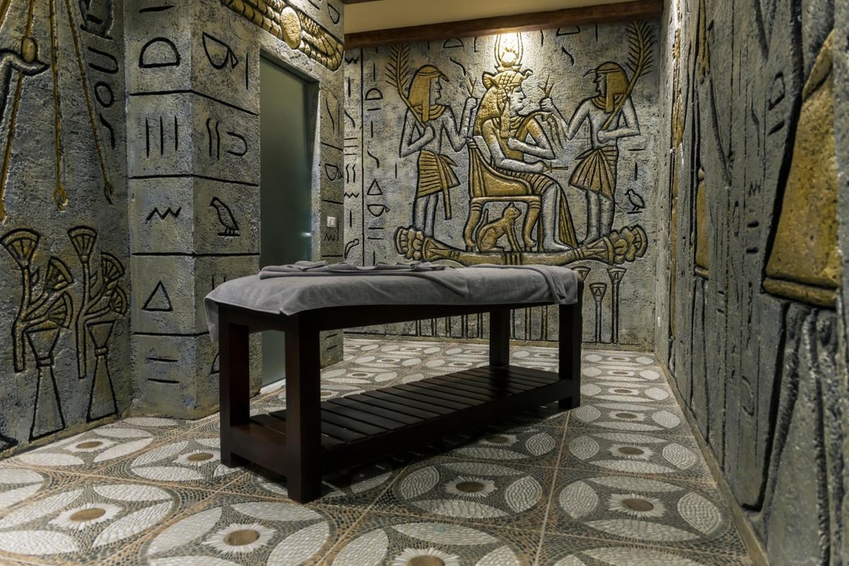Sunrise Diamond Beach Resort Grand Select spa treatment room with a massage table and hieroglyphic wall carvings.