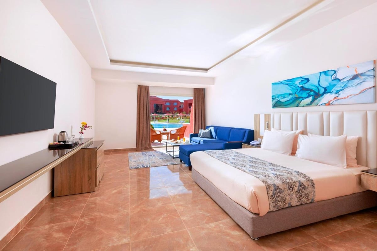 Pickalbatros Laguna Vista Aqua Park guest room with a large bed and blue sofa.