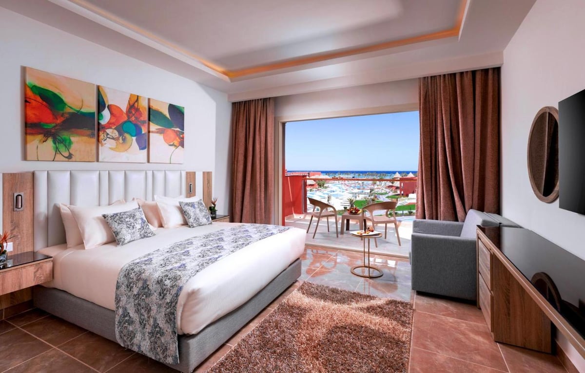 Pickalbatros Laguna Vista Aqua Park guest room with a bed and a balcony overlooking the sea.