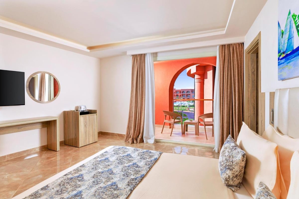 Pickalbatros Laguna Vista Aqua Park guest room with a bed and arched terrace doorway.