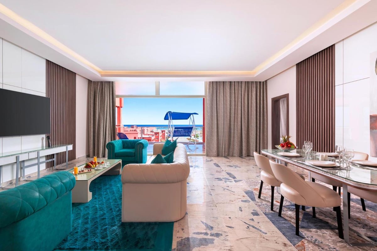 Pickalbatros Laguna Vista Aqua Park suite living room with teal sofas and a dining table.