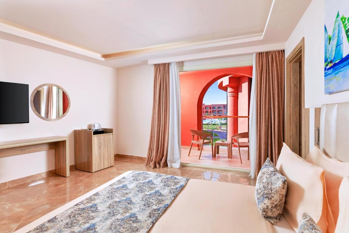 Pickalbatros Laguna Vista Aqua Park bedroom with a bed and an arched balcony opening.