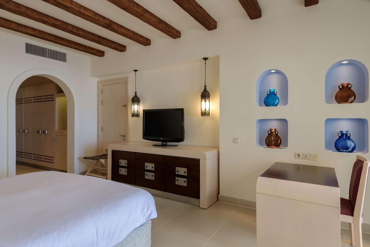 Hilton Marsa Alam Nubian Resort bedroom with wooden ceiling beams and recessed wall niches.