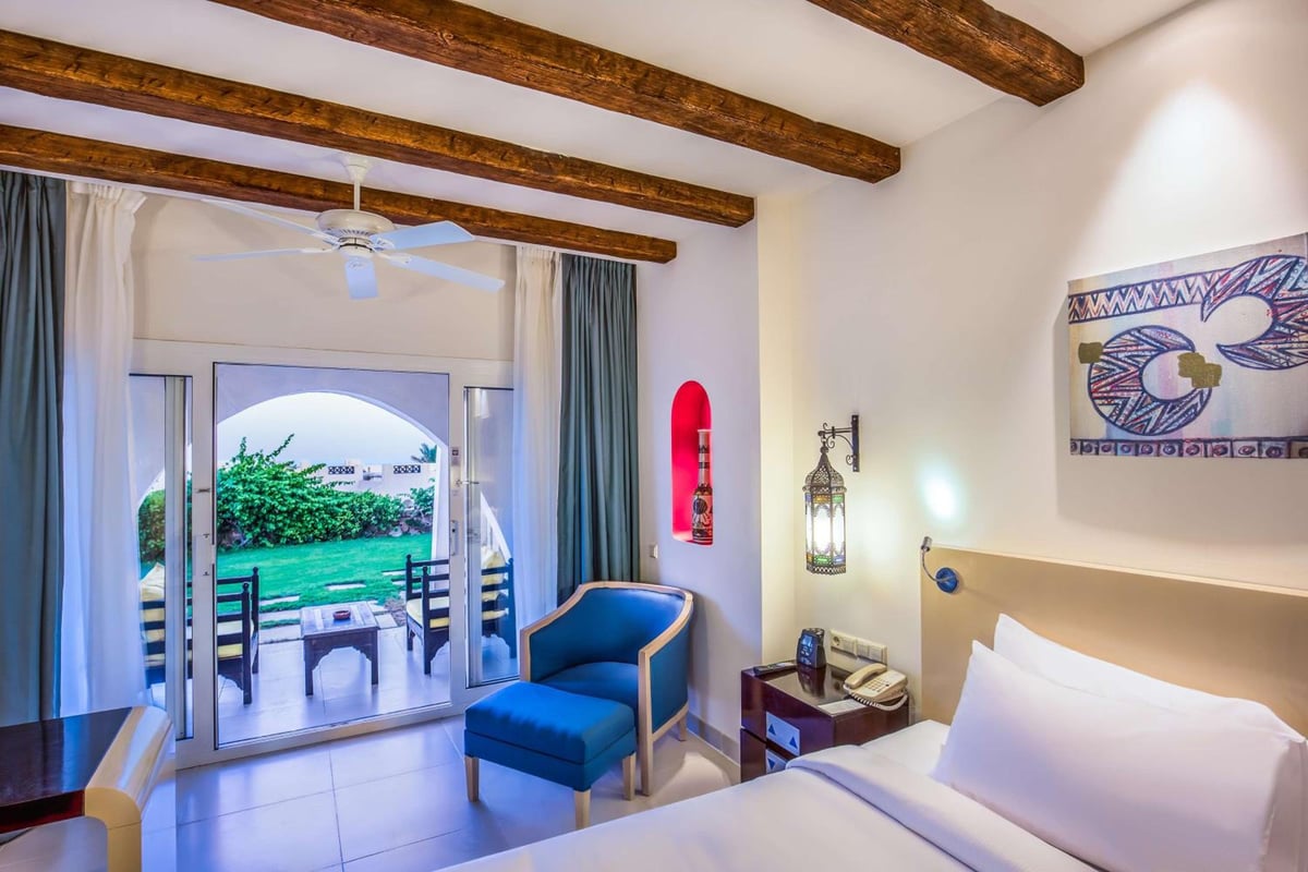 Hilton Marsa Alam Nubian Resort guest room with wooden ceiling beams and sliding glass doors.
