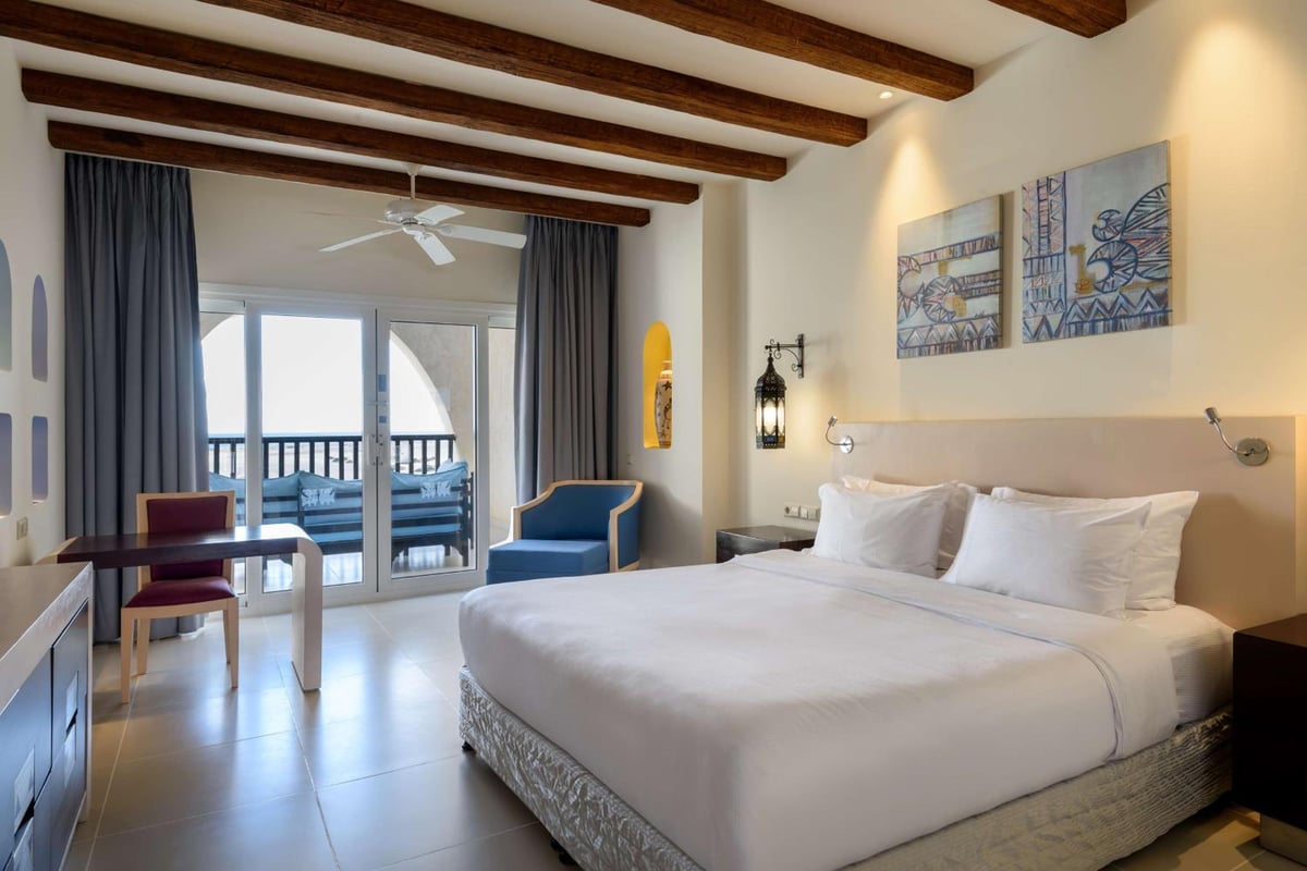 Hilton Marsa Alam Nubian Resort guest room with a white bed and balcony doors.