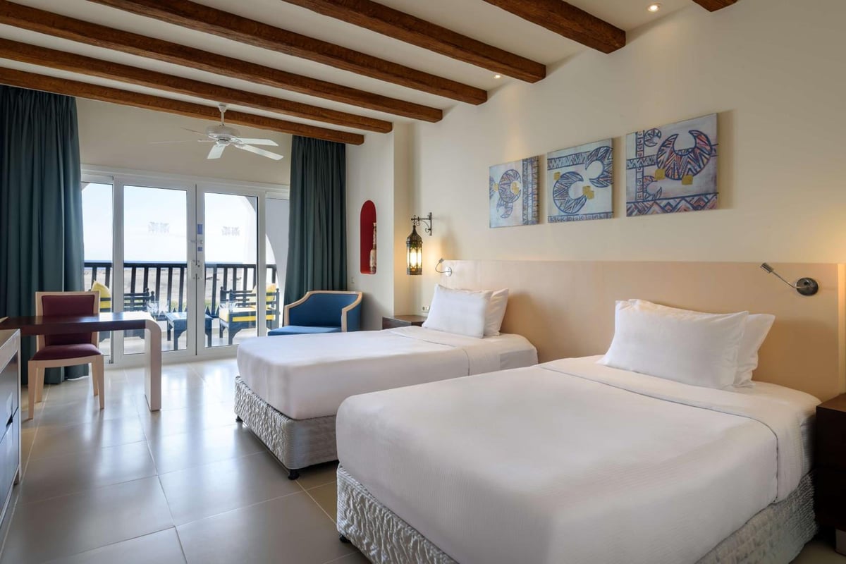 Hilton Marsa Alam Nubian Resort twin bedroom with two beds and exposed ceiling beams.