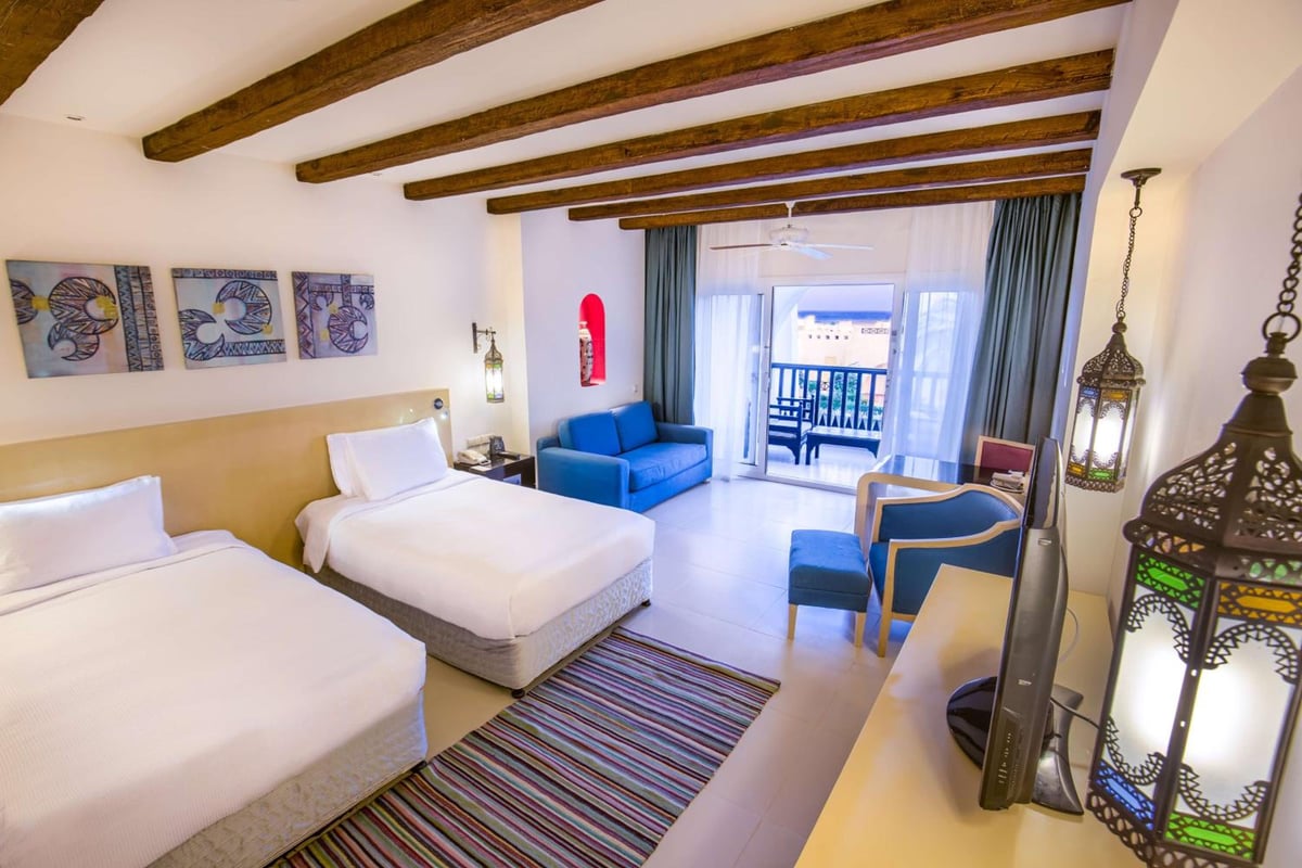 Hilton Marsa Alam Nubian Resort twin room with two beds and exposed wooden ceiling beams.