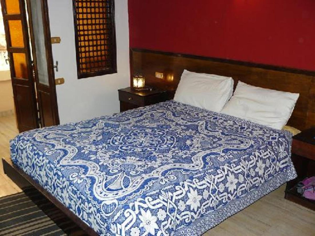 El Nakhil Hotel Luxor bedroom with a patterned double bed and wooden headboard.