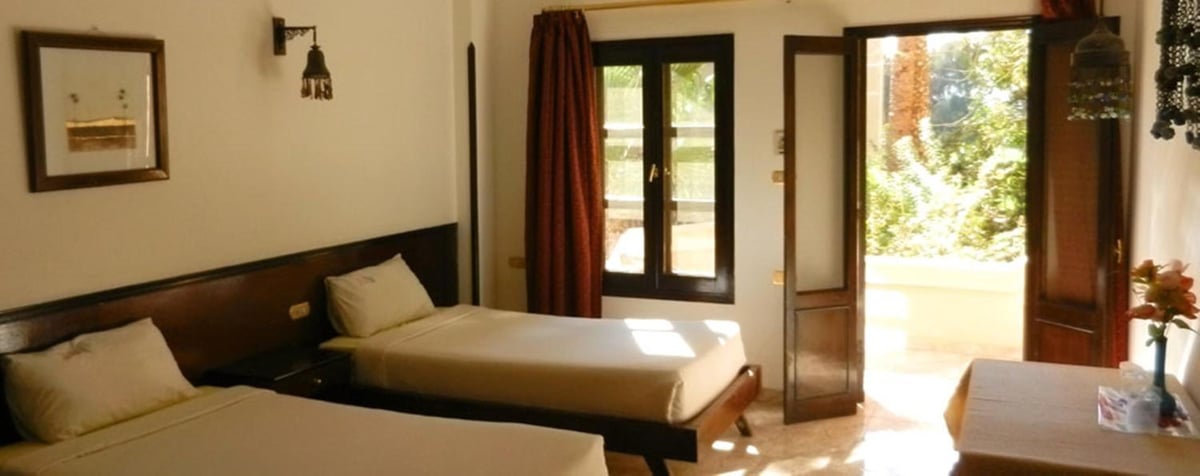 El Nakhil Hotel Luxor guest room with two beds and open doors to an outdoor terrace.
