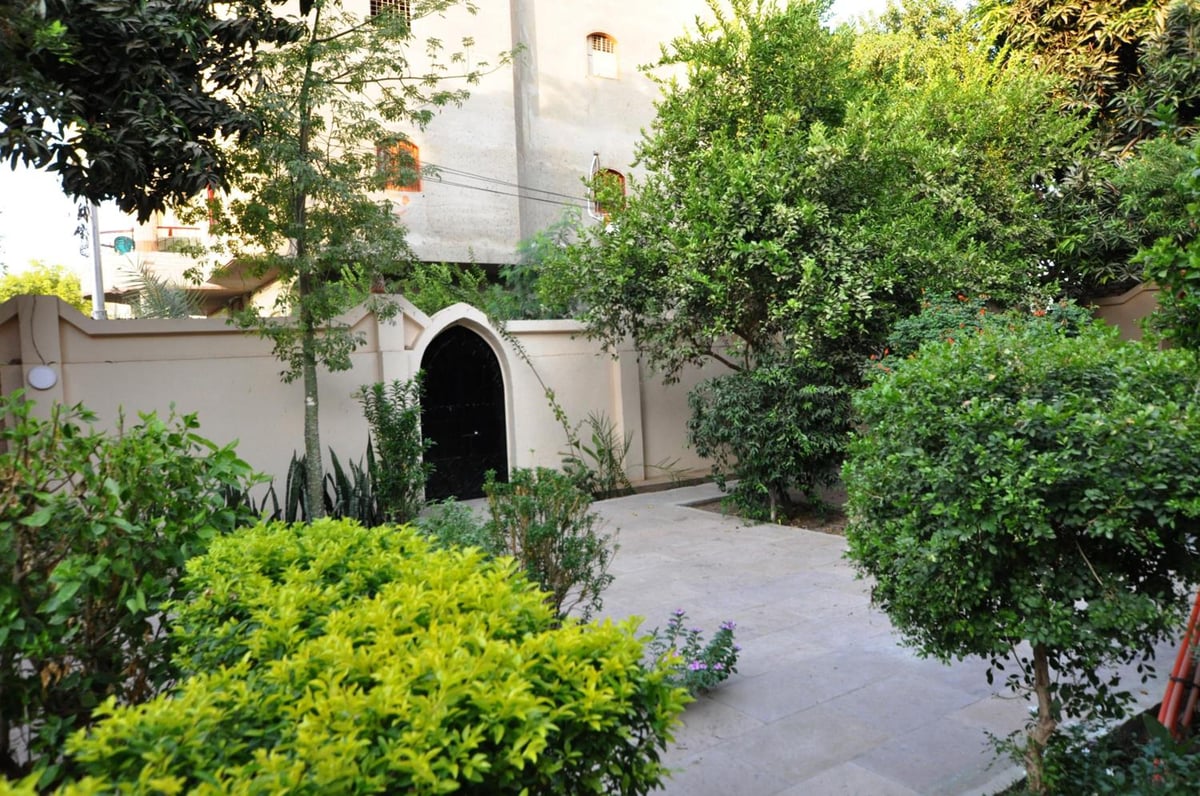 El Nakhil Hotel Luxor courtyard with leafy plants and an arched entrance.