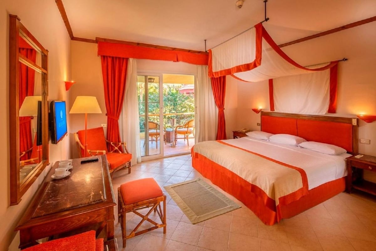 Siva Grand Beach bedroom with a draped canopy bed and sliding glass doors.