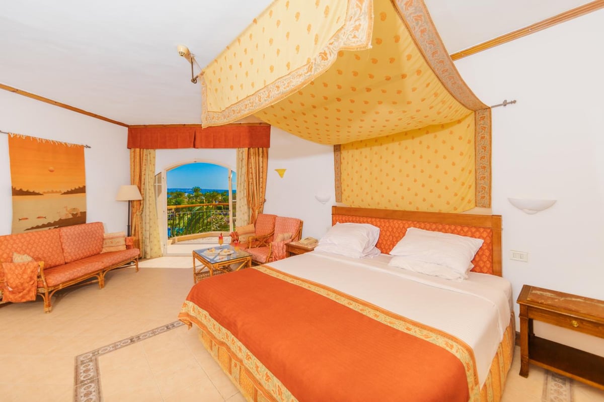 Siva Grand Beach bedroom with a canopy bed and balcony doors.