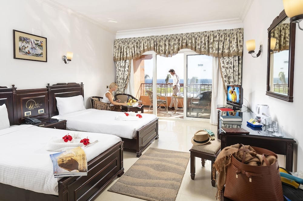 Three Corners Happy Life Beach Resort twin room with two beds and balcony doors.