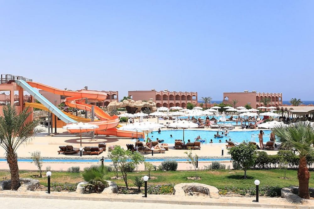 Three Corners Happy Life Beach Resort pool area with water slides and sun loungers.