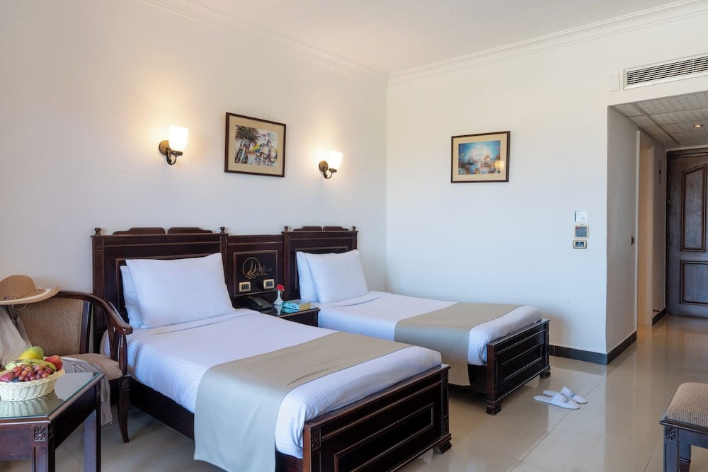 Three Corners Happy Life Beach Resort twin bedroom with two single beds and framed wall art.