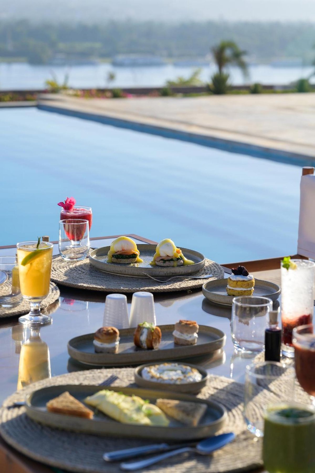 The Zen Wellness Resort Aswan poolside dining area with a swimming pool and plated dishes.
