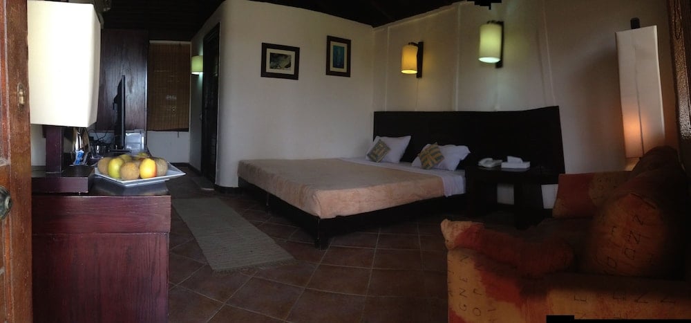 Abu Dabbab Lodge bedroom with a bed and an armchair.