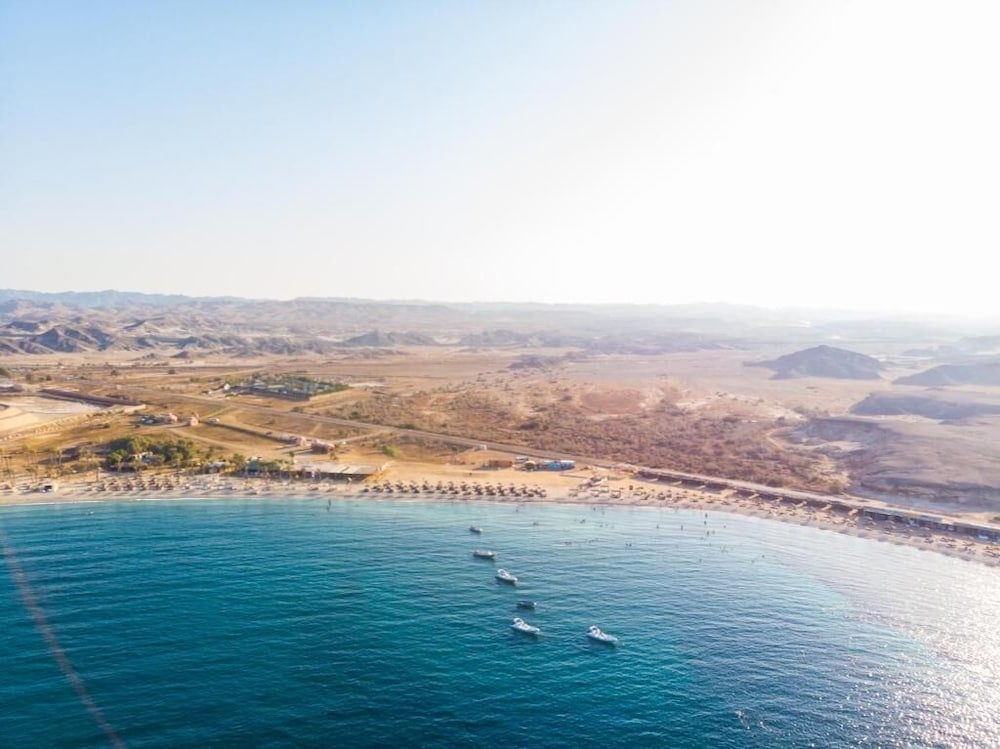 Abu Dabbab Lodge beach with turquoise water and desert hills.